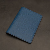 Blue leather passport holder on a dark grey background