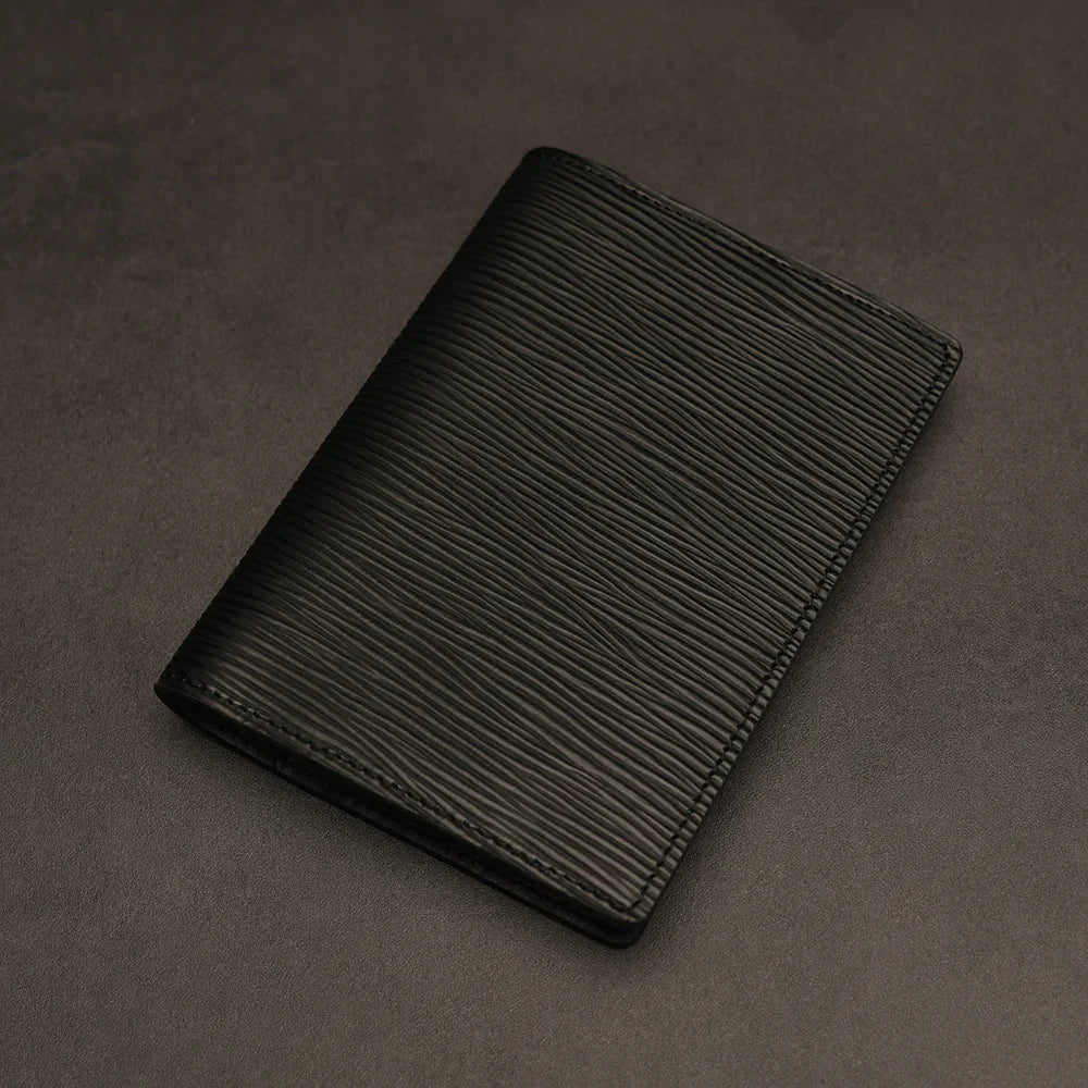 Black leather passport holder on a dark grey background