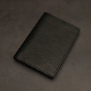 Black leather passport holder on a dark grey background