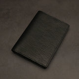 Black leather passport holder on a dark grey background