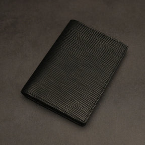 Black leather passport holder on a dark grey background