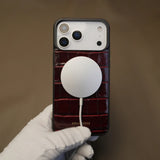 Crocodile pattern iPhone case with a magsafe held by a gloved hand against a brown background 