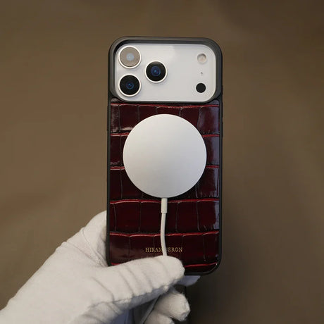 Crocodile pattern iPhone case with a magsafe held by a gloved hand against a brown background 