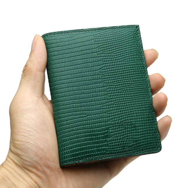 Hand holding a green lizard pattern slim wallet against a white background