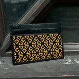 Black cardholder with yellow geometric pattern on a textured surface