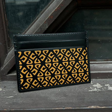 Black cardholder with yellow geometric pattern on a textured surface