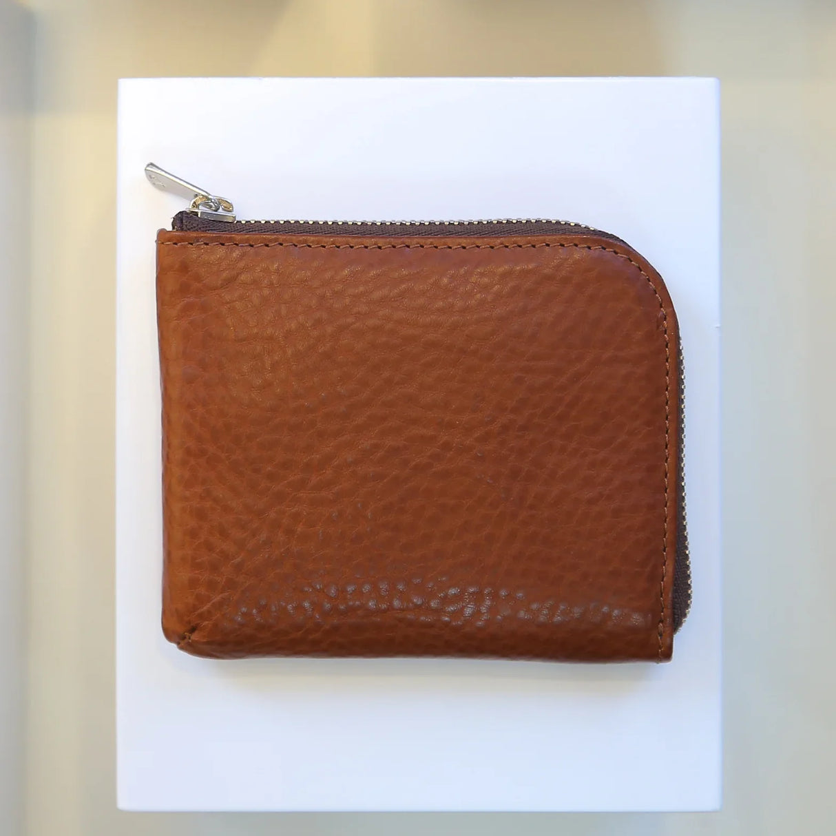 Brown vegetable tanned leather coin wallet with a zipper on a white background