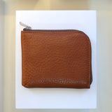 Brown vegetable tanned leather coin wallet with a zipper on a white background