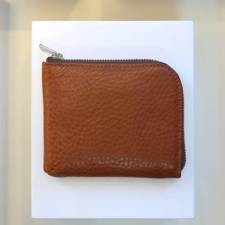 Brown vegetable tanned leather coin wallet with a zipper on a white background