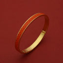 Luxury gold bangle with orange textured inlay, sleek design for elegant wristwear