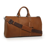 Brown vegeetable tanned leather holdall bag with a shoulder strap on a white background