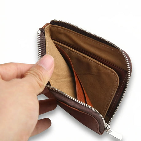 Brown leather coin wallet with a hand opening it on a white background