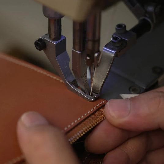 Skilled artisan at Hiram Beron boutique factory performing precise hand-finishing on premium leather. Representing 14 years of manufacturing excellence and uncompromising quality control in Guangzhou, China