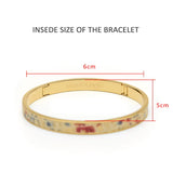 Gold bangle bracelet with floral enamel design, 6cm x 5cm inside dimensions, Horologii engraving