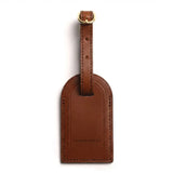 Brown leather luggage tag with gold accent on a white background
