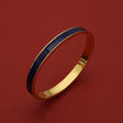 Gold bangle with navy blue enamel inlay, luxury bracelet for women, elegant accessory on red background