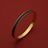 Gold bangle with black textured inlay, engraved 'HOROLOGII', luxury accessory on red background