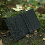 Black pebble leather wallet on a natural background with greenery