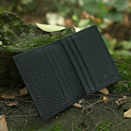 Black pebble leather wallet on a natural background with greenery