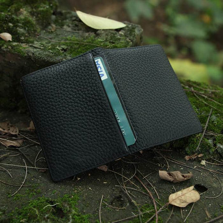 Black leather wallet with a card on a mossy surface